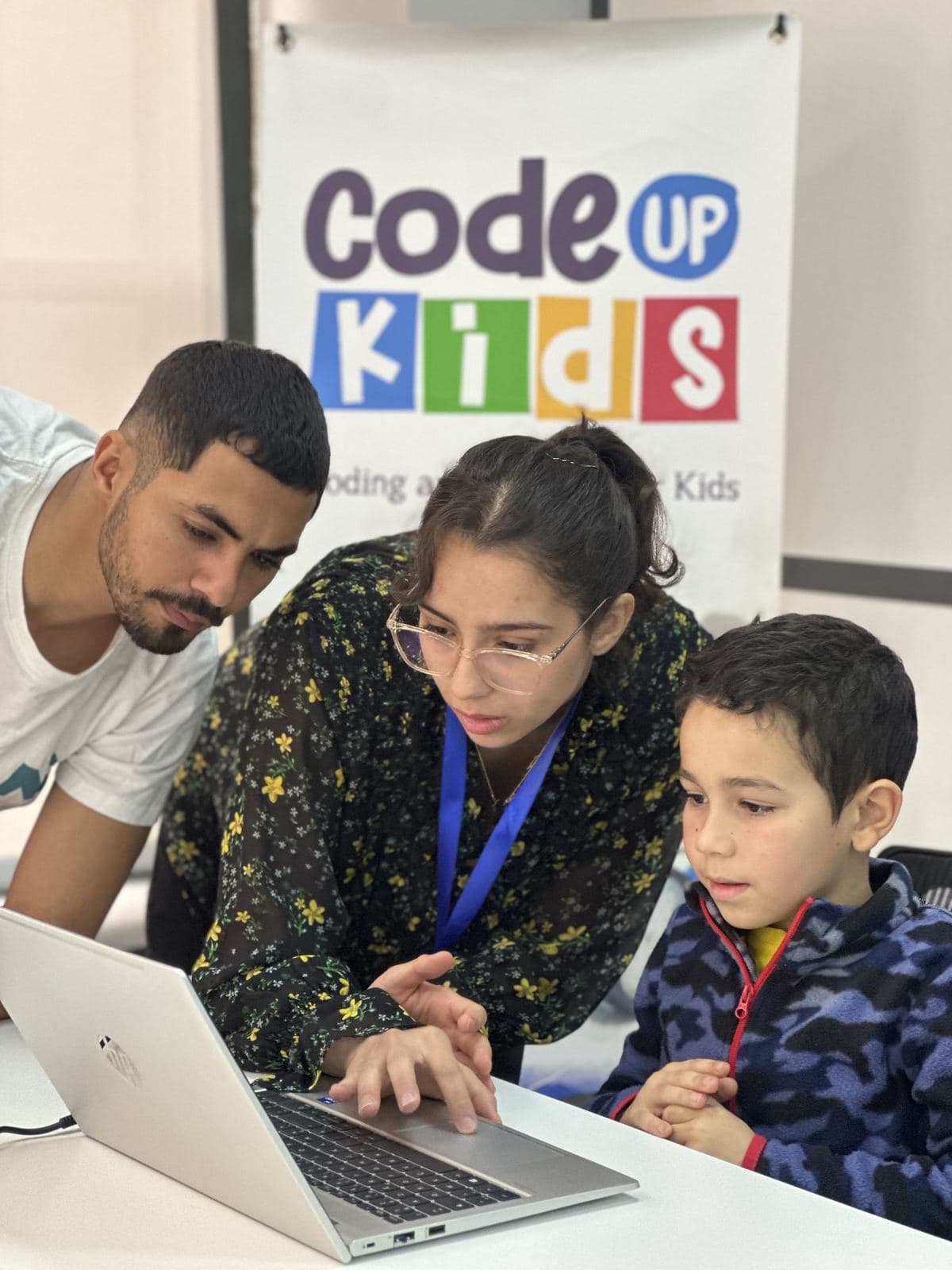 Un coach Code Kids accompagne deux enfants sur ordinateur